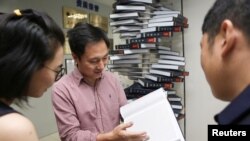FILE - Scientist He Jiankui shows "The Human Genome", a book he edited, at his company Direct Genomics in Shenzhen, Guangdong province, China August 4, 2016. (REUTERS)
