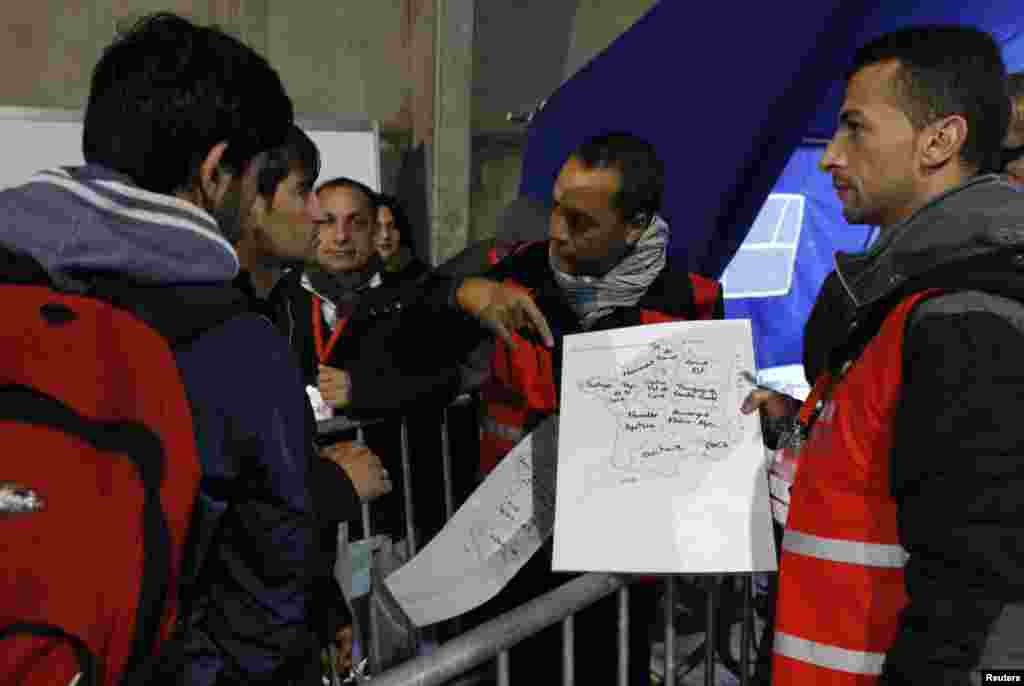 Migrants look at a map of France at a processing center to be registered on the second day of their evacuation and transfer to reception centers in France, during the dismantlement of the camp called "the jungle" in Calais, France, Oct. 25, 2016. 