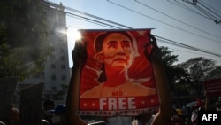 FILE - In this Feb. 15, 2021, photo, a protester holds up a poster featuring Aung San Suu Kyi during a demonstration against the military coup at in front of the Central Bank of Myanmar in Yangon.