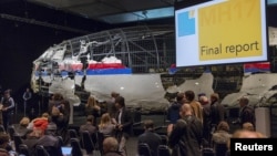 El avión de Malaysian Air sirve como fondo para la conferencia de prensa en la que se presentó el reporte final de la Junta de Seguridad holandesa.