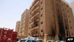 Kuwaiti firefighters and security forces gather outside a building which was ingulfed by fire, in Kuwait City, on June 12, 2024.