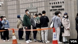 多名在西九龍裁判法院外輪候旁聽席的人士背對鏡頭。(美國之音湯惠芸)