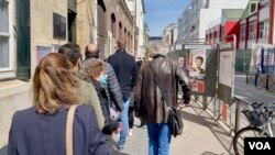 Personas esperan para votar en la primera vuelta de las elecciones presidenciales en el norte de París. [Lisa Bryant/VOA]