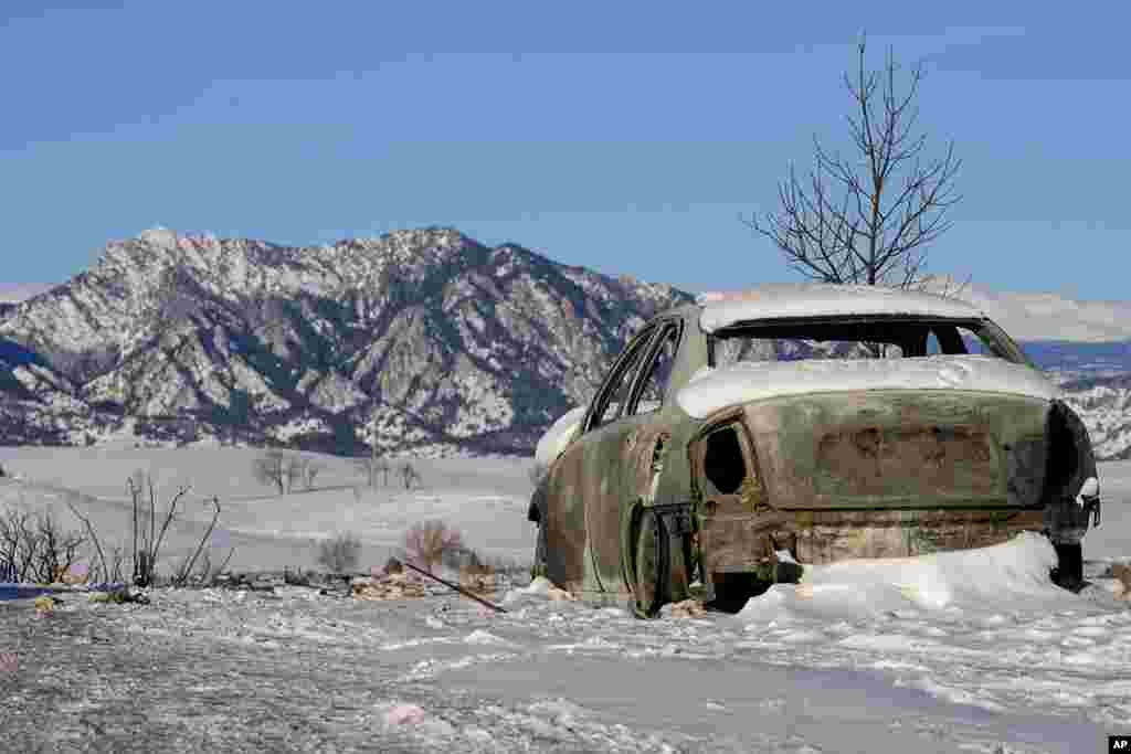 Snow covers the burned remains of a car after wildfires ravaged the area in Superior, Colorado.