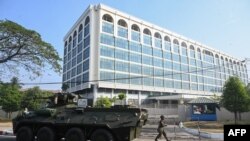 စစ်အာဏာသိမ်းပြီးနောက် ရန်ကုန်မြို့ဗဟိုဘဏ်အပြင်ဘက်မှာ သံချပ်ကာတင့်ကားနဲ့ စစ်သည်တဦးကိုတွေ့ရစဉ်။ (ဖေဖေါ်ဝါရီ ၁၅၊ ၂၀၂၁)