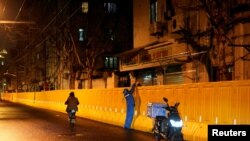 一名快遞員在上海封城後給一戶人家在圍欄上遞送食物。（2022年3月31日）