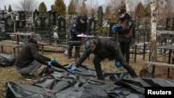 Empleados de servicios funerarios e investigadores policiales trabajan con cuerpos de civiles, recogidos de las calles y llevados al cementerio local, mientras continúa el ataque de Rusia contra Ucrania, en la ciudad de Bucha, Ucrania, 6 de abril de 2022. REUTERS/Oleg Pereverzev
