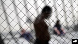 FILE - In this May 26, 2010 file photo, men sit in the sun in the health ward at the Otay Mesa immigration detention center in San Diego.