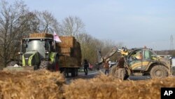Agricultores instalan fardos de heno en una carretera cerca del aeropuerto principal de París, el lunes 29 de enero de 2024, cerca de Roissy-en-France, al norte de París.