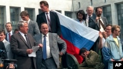FILE - In this Aug. 19, 1991, photo, Boris Yeltsin, foreground left, at the time president of the Russian constituent republic within the Soviet Union, addresses a crowd standing atop of a tank in front of the "Russian White House," in Moscow, Russia.