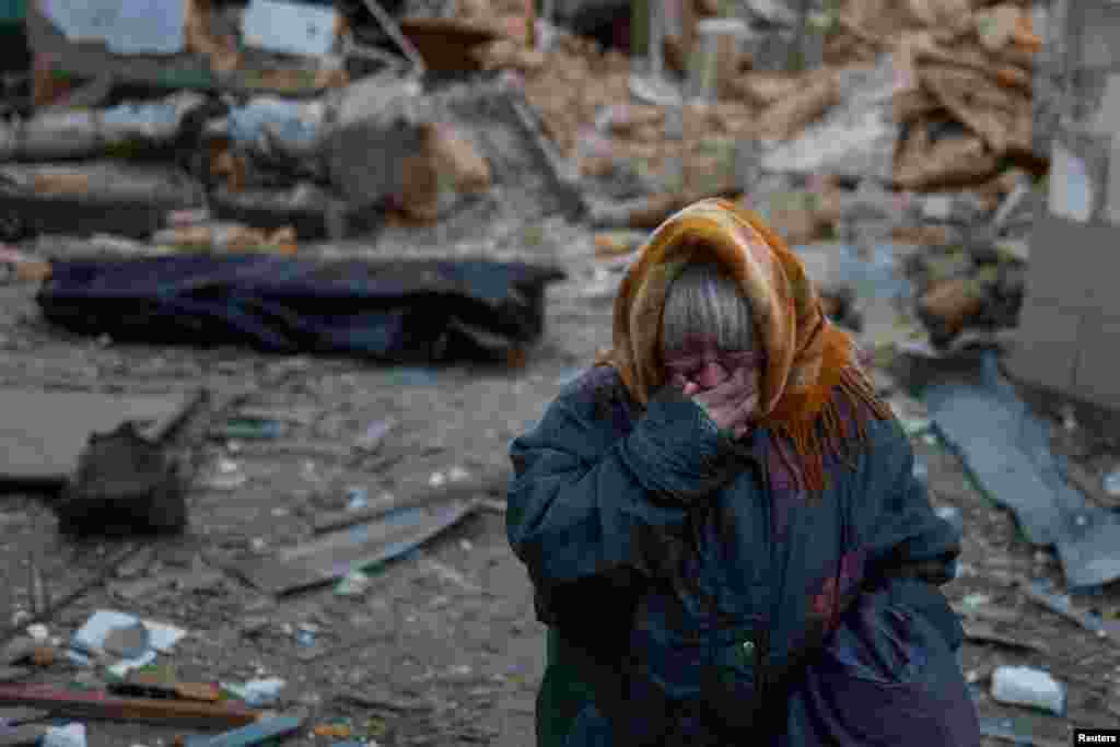 A woman reacts next to the body of her neighbor found under debris of a residential house destroyed by a Russian missile attack in Mykolaiv, Ukraine.