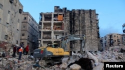 La gente se reúne entre los escombros mientras continúa la búsqueda de sobrevivientes, después del terremoto, en Alepo, Siria, el 7 de febrero de 2023. 