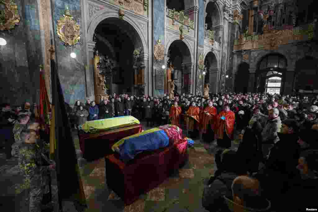 People attend a memorial service to pay their respects to Viktor Dudar and Ivan Koverznev, Ukrainian servicemen killed on March 2, during Russia's invasion of Ukraine, in a Jesuit Church (Church of the Most Holy Apostles Peter and Paul) in central Lviv.