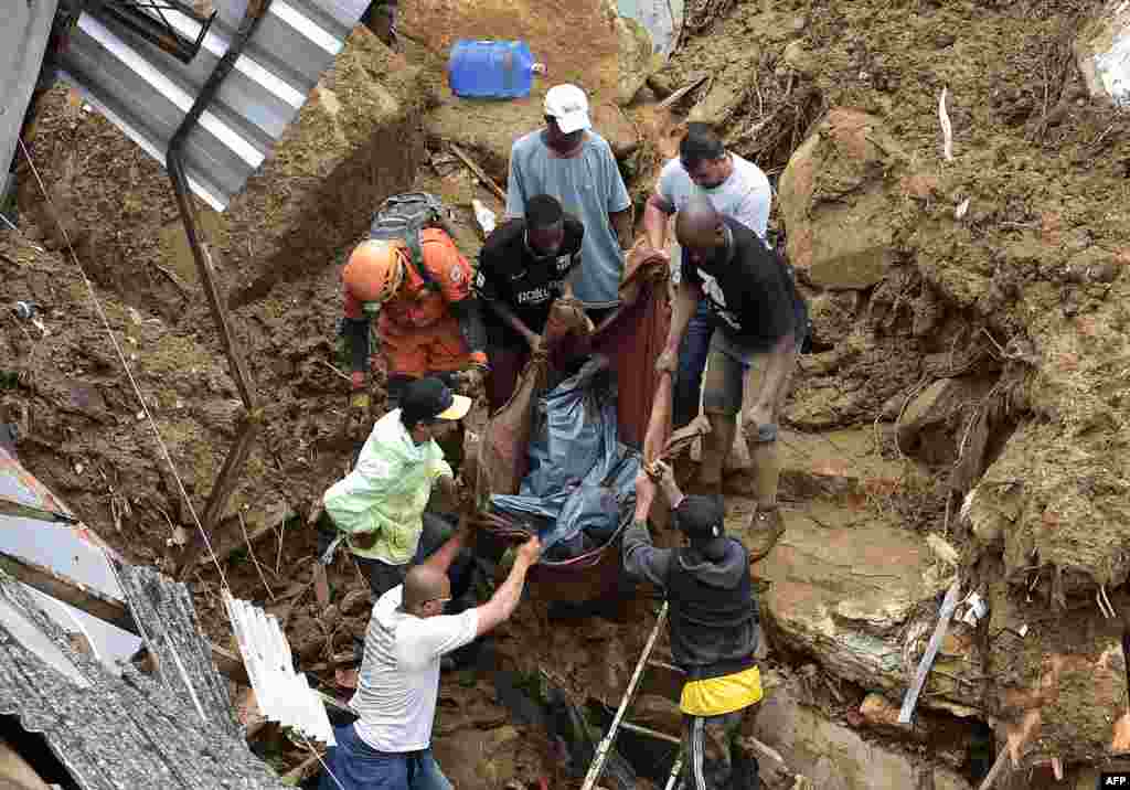 People carry a victim's body out of the rubble after a mudslide in Petropolis, Brazil.&nbsp;Large scale flooding destroyed hundreds of properties and claimed at least 34 lives in the area.