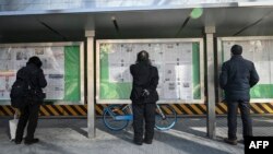 FILE - A man, center, reads the Chinese state-run newspaper with coverage of the conflict between Russia and Ukraine, on a street in Beijing, Feb. 24, 2022.