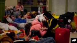 Une religieuse réconforte un enfant dans un abri pour personnes déplacées fuyant l'Ukraine, à Przemysl, en Pologne, le 8 mars 2022. (AP Photo/Daniel Cole)