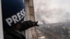 Associated Press photographer Evgeniy Maloletka points at the smoke rising after an airstrike on a maternity hospital, in Mariupol, March 9, 2022. (AP Photo/Mstyslav Chernov)