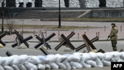 A member of Ukraine's Territorial Defense Forces, the military reserve of Ukraine's Armed Forces, stands guard next to anti-tank barriers blocking a street in Kyiv, March 6, 2022.