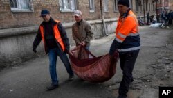 2022年3月23日，在乌克兰基辅，邻居们从被炮击的公寓里搬出被打碎的窗户玻璃碎片。（美联社）