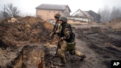 Ukrainian soldiers inspect trenches used by Russian soldiers during the occupation of villages on the outskirts of Kyiv, Ukraine.
