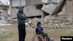 Mahmoud Madarati, 55, poses as he stands near his son whose leg and hand were amputated after sustaining injuries by what Mahmoud says was shelling from government-held areas, northern Syria, March 3, 2022. 