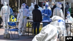 CHINA-HEALTH-VIRUSWorkers and volunteers look on in a compound where residents are tested for the Covid-19 coronavirus during the second stage of a pandemic lockdown in Jing' an district in Shanghai on April 4, 2022. (Photo by Hector RETAMAL / AFP)