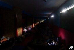 Ljudi se pripremaju za noć u improvizovanom skloništu od bombi u sportskom centru u Mariupolju, u nedjelju kasno uveče, 27. februara 2022. (AP Photo/Mstislav Černov)