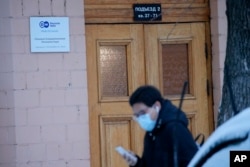 A journalist walks past a sign of the Moscow office of German public broadcaster Deutsche Welle in Moscow, Russia, Feb. 4, 2022.