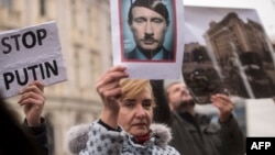 FILE - A protester holds a photo depicting Russian President Vladimir Putin as Adolf Hitler during a demonstration against Russia's invasion of the Ukraine, in Skopje, North Macedonia, March 6, 2022.