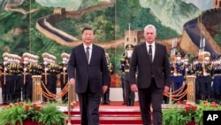 In this photo released by China's Xinhua News Agency, Chinese President Xi Jinping, left, and Cuba's President Miguel Diaz-Canel Bermudez walk during a welcome ceremony at the Great Hall of the People in Beijing, Friday, Nov. 25, 2022.