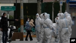 Workers in protective gear gather for their duties in Beijing, Nov. 28, 2022. 