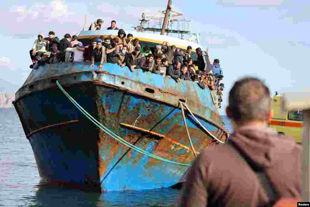 Migrants stand onboard a fishing boat at the port of Paleochora, following a rescue operation off the island of Crete, Greece.