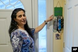 Koloud "Kay" Tarapolsi pokazuje na držač za maske koji je napravila njena kćerka i na kojem je na arapskom napisana fraza "Za vaše zdravlje", u njenom domu u Redmondu, u državi Washington. (Foto: AP/Ted S. Warren)