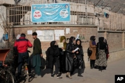 FILE - Afghan women students stand outside the Kabul University in Kabul, Afghanistan, Dec. 21, 2022. Taliban security forces are upholding a higher education ban for women by blocking access to university campuses.