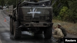 Ukrainian servicemen inspect a destroyed Russian military vehicle, as Russia's attack on Ukraine continues, in Kharkiv region, Ukraine, Sept. 13, 2022. 