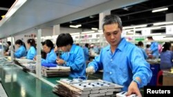 FILE - Employees work on a production line manufacturing lithium battery products at a factory in Yichang, Hubei province, China May 28, 2019.