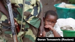 Mtoto msichana akiwa ameshika mkono wa mpiganaji wa kundi la waasi la M23. Karuba, Goma. Nov 28,2012