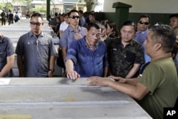 Philippine President Rodrigo Duterte, center, touches one the caskets of some of the victims of the bombings, Jan. 26, 2018, of a Roman Catholic Cathedral on Jolo, Sulu province in southern Philippines, during his visit Monday.