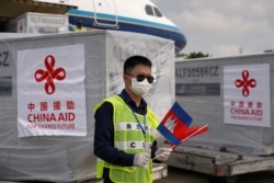 បុគ្គលិកប្រចាំអកាសយានដ្ឋានអន្តរជាតិភ្នំពេញម្នាក់កាន់ទង់ជាតិកម្ពុជានិងចិន ខណៈយន្តហោះដឹកក្រុមគ្រូពេទ្យចិន និងសម្ភារៈបរិក្ខាពេទ្យពីប្រទេសចិន បានមកដល់កម្ពុជា ដើម្បីជួយកម្ពុជាក្នុងការប្រយុទ្ធនឹងការឆ្លងរាលដាលនៃវីរុសកូរ៉ូណា ឬកូវីដ១៩ នៅរាជធានីភ្នំពេញ ថ្ងៃទី២៣ ខែមីនា ឆ្នាំ២០២០។