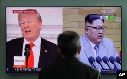 FILE - A man watches a TV screen showing file footages of U.S. President Donald Trump, left, and North Korean leader Kim Jong Un during a news program at the Seoul Railway Station in Seoul, South Korea, March 27, 2018.