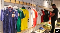 In this June 5, 2018 photo a customer looks at different national soccer team jerseys that are on display at a shop in London. With just days to go before the FIFA World Cup, some winners and losers have emerged among the often wild and wacky team jerseys