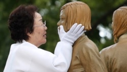 In this Aug. 14, 2019, file photo, Lee Yong-soo, who was forced to serve for the Japanese troops as a sex slave during World War II, touches the face of a statue of a girl symbolizing the issue of wartime "comfort women" during its unveiling ceremony in Seoul.