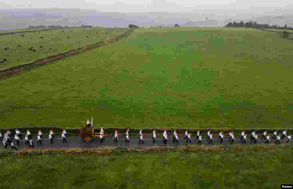 A drone view shows locals wearing straw hats pull a cart carrying reeds through the village during the annual 'rushbearing' festival in Sowerby Bridge, Britain.