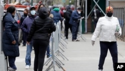 People stand in line as they wait to get tested for COVID-19 at a just-opened testing center in the Harlem section of New York, April 20, 2020.