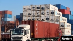  2019 年12月12日，一名工人在中国天津港附近的物流中心驾驶一辆载有集装箱的卡车。图片来源：路透社