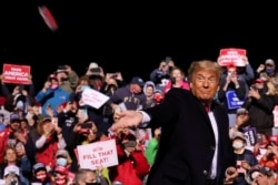 U.S. President Donald Trump throws face masks to the crowd as he arrives to hold a campaign rally at John Murtha Johnstown-Cambria County Airport in Johnstown, Pennsylvania, Oct. 13, 2020.