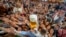 Young people reach out for free beer in one of the beer tents on the opening day of the 187th Oktoberfest beer festival in Munich, Germany, Sept. 17, 2022. 