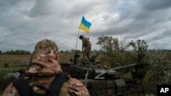 Un militar de la guardia nacional ucraniana se para sobre un tanque ruso destruido en un área cerca de la frontera con Rusia, en la región de Kharkiv, Ucrania, el 19 de septiembre de 2022.