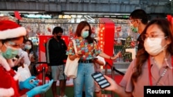 មនុស្សម្នា​​នាំ​គ្នា​វាស់​កម្តៅ​ក្នុង​ខ្លួន​ ខណៈ​ដែល​ពួកគេ​ទៅ​មើល​ការ​តុបតែង​ភ្លើង​សម្រាប់​ថ្ងៃ​បុណ្យ​ណូអែល ទីក្រុង​បាងកក ប្រទេស​ថៃ ថ្ងៃទី២៤ ខែធ្នូ ឆ្នាំ២០២០។ 