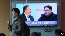 A South Korean army soldier passes by a TV screen showing file footage of CIA Director Mike Pompeo, left, and North Korean leader Kim Jong Un during a news program at the Seoul Railway Station in Seoul, South Korea, Wednesday, April 18, 2018. (AP Photo/Ahn Young-joon)